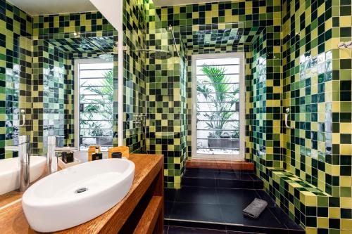 ein Badezimmer mit grünen und gelben Fliesen und einem Waschbecken in der Unterkunft Chalet Estoril Luxury Apartments in Estoril