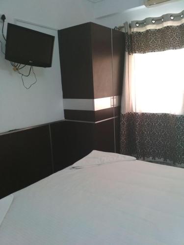 a bedroom with a bed and a television on the wall at Sai Pavilion in Puttaparthi