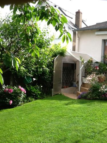 une arrière-cour d'une maison avec de l'herbe verte et des fleurs dans l'établissement Agora Mijo Chambre d'Hôtes, à Nantes