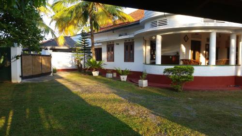 a white house with palm trees in the yard at Ahangama Eco Villa in Ahangama
