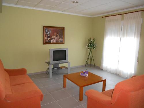 Hostal Donaire II في توميلوسو: غرفة معيشة مع كراسي برتقالية وتلفزيون
