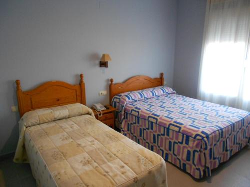 1 dormitorio con 2 camas y ventana en Hostal Donaire II, en Tomelloso