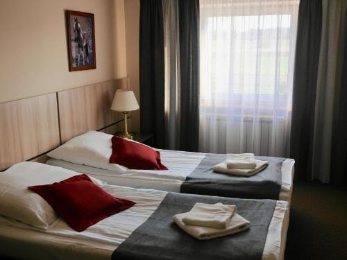 two beds in a hotel room with towels on them at Hotel Stajnia Wolica in Wolica