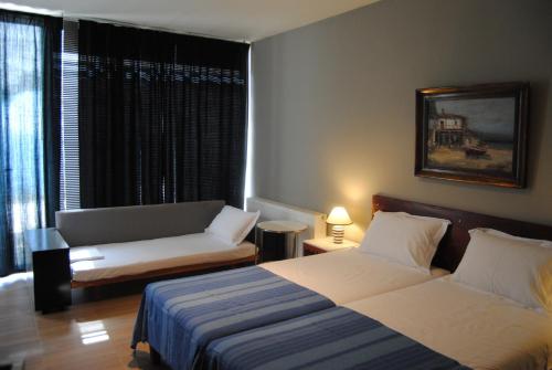 a bedroom with two beds and a couch and a window at Leonidionhouses - The Ogra House in Leonidion