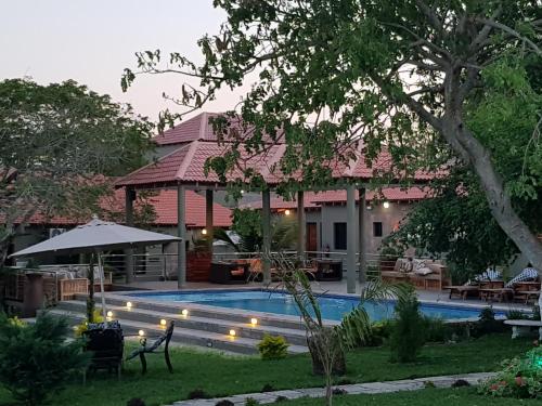a house with a swimming pool in a yard at Ossanzaia Bilene Lodge in Vila Praia Do Bilene