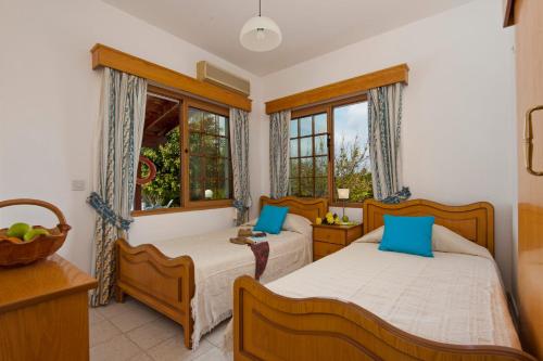 two beds in a room with two windows at Panareti Coral Bay Villas in Coral Bay