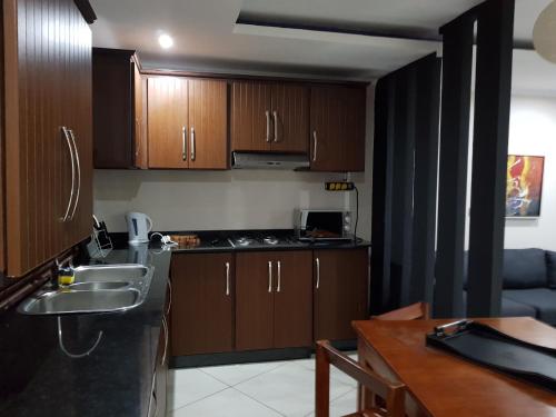 a kitchen with wooden cabinets and a sink and a table at Ossanzaia Bilene Lodge in Vila Praia Do Bilene