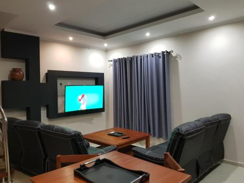 a waiting room with a tv and a table and chairs at Ossanzaia Bilene Lodge in Vila Praia Do Bilene