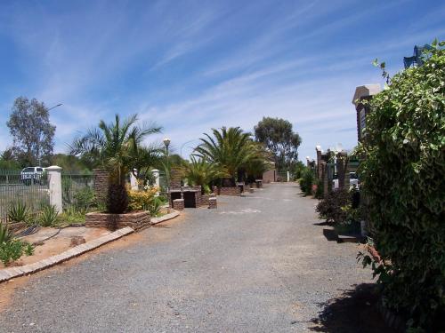 a driveway lined with plants and a fence at Gables Inn in Colesberg