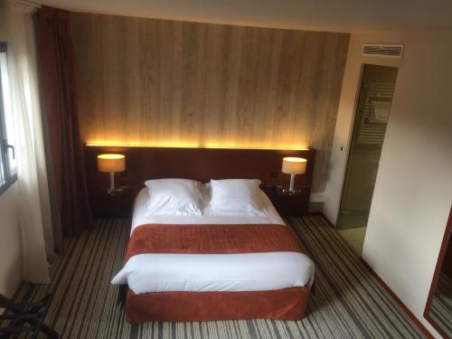 a hotel room with a large bed with two lamps at Hotel du Casino in Saint-Valéry-en-Caux