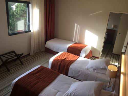 a hotel room with three beds and a mirror at Hotel du Casino in Saint-Valéry-en-Caux