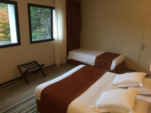 a hotel room with two beds and two windows at Hotel du Casino in Saint-Valéry-en-Caux