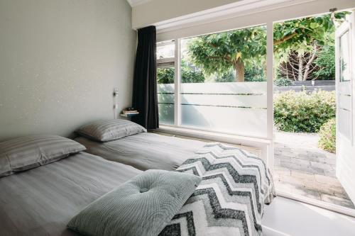 a bedroom with two beds and a large window at Kranenbergh Boutique Apartments in Bergen