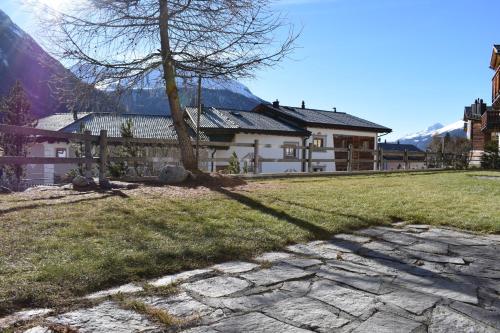 a house with a tree and a stone walkway at Residence Miragolf in Madulain