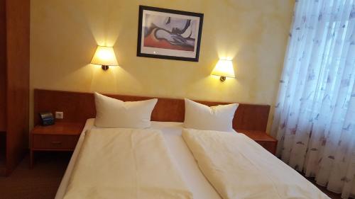 um quarto com 2 camas com lençóis brancos e 2 candeeiros em Hotel Restaurant Schlosschänke em Hannoversch Münden