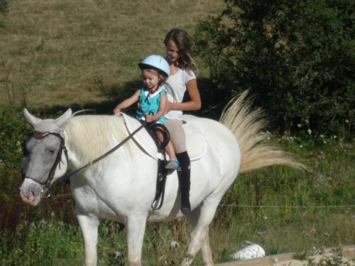 a woman and a little girl riding on a white horse at Gite Gabriela in Bassignac-le-Haut