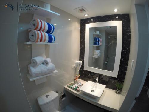 a bathroom with a sink and a mirror and a toilet at Riganna Two @ Shell Residences - near Airport, MOA in Manila