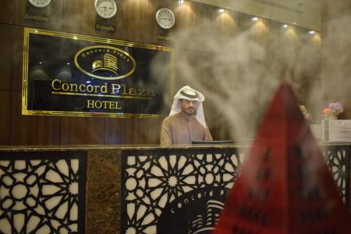 a man standing in front of a window with a sign at Concord Plaza in Hafr Al Baten