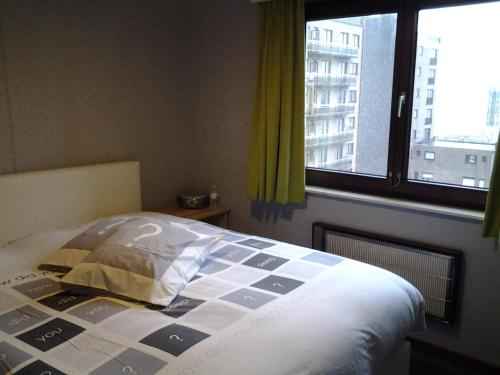 Ce lit se trouve dans une chambre dotée d'une grande fenêtre. dans l'établissement Zonnig Appartement met Zeezicht, à Coxyde