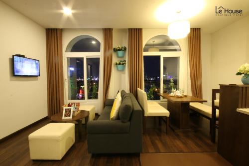 a living room with a couch and a table and windows at Le House Boutique Hotel - 100m to the beach in Da Nang