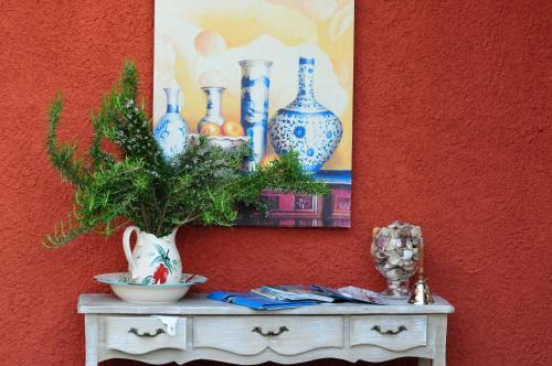 a table with vases and a painting on a wall at Dendrolivano in Minia