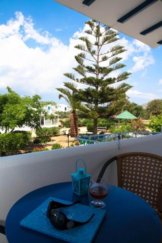 a blue table with a glass of wine on a balcony at Maroussa Studios in Agia Anna Naxos