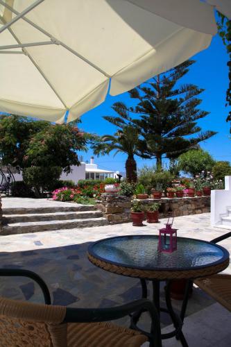 a table and chairs under a white umbrella at Maroussa Studios in Agia Anna Naxos