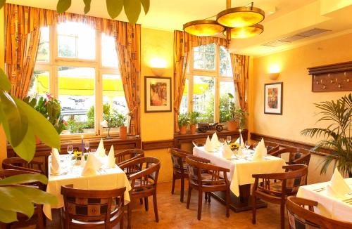 um restaurante com mesas e cadeiras brancas e janelas em Hotel Restaurant Schlosschänke em Hannoversch Münden