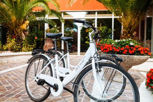 a white bike parked on a sidewalk next to flowers at Hotel Savoy Palace - Tonelli Hotels in Riva del Garda
