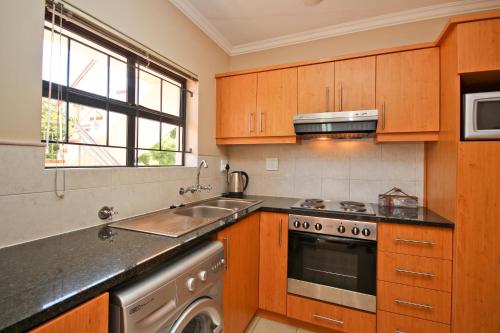 a kitchen with wooden cabinets and a sink and a stove at Vilaroux in Stellenbosch