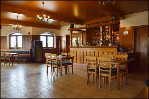 a restaurant with wooden tables and chairs and a bar at Penzion Starý dvůr in Nové Dvory