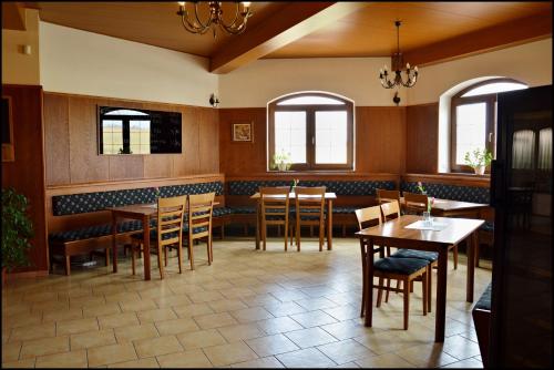 a dining room with tables and chairs and windows at Penzion Starý dvůr in Nové Dvory