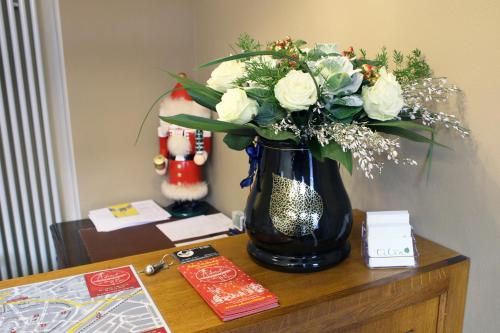 a black vase filled with white flowers on a table at Hotel garni Tilia in Quedlinburg