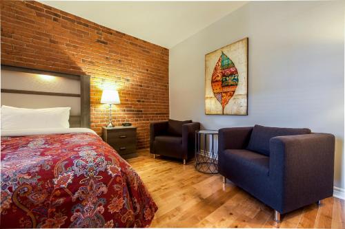 a hotel room with a bed and two chairs at Auberge de La Fontaine in Montréal