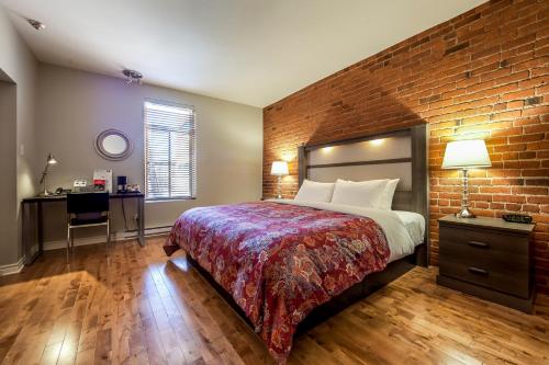 a bedroom with a large bed and a brick wall at Auberge de La Fontaine in Montréal