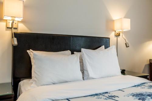 a bedroom with a bed with white pillows and two lamps at Auberge de La Fontaine in Montréal