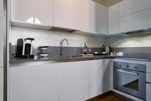 フィレンツェにあるLuxury Apartment Rucellaiの白いキャビネットとシンク付きのキッチン