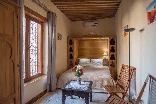 Un dormitorio con una cama y una mesa con un jarrón de flores en Dar Essoaoude - Fes Nejjarine, en Fez