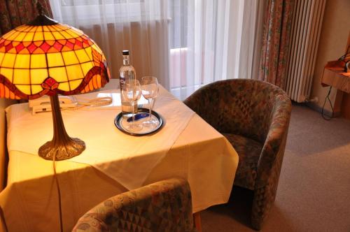 a table with a lamp and wine glasses on it at Hotel Schick in Bad Wörishofen