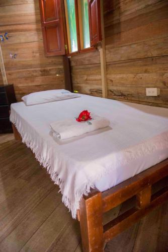 a bed with two towels and a red flower on it at Posadas Ecoturisticas Seineken in El Zaino