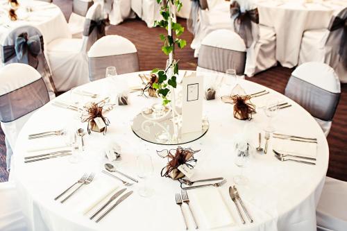 a table with white tables and chairs with silverware at Leonardo Hotel Newcastle Quayside in Newcastle upon Tyne