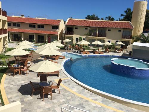 a swimming pool with tables and chairs and umbrellas at Loft Solar Água in Pipa