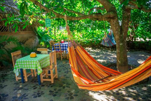 a hammock with a table and chairs under a tree at Posadas Ecoturisticas Seineken in El Zaino