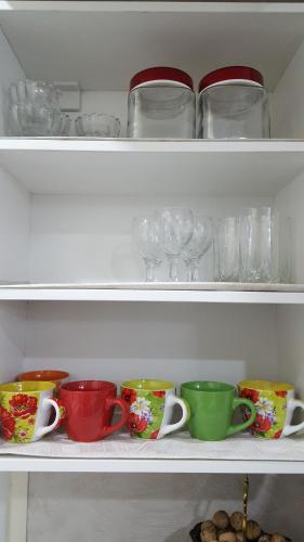 a shelf filled with colorful cups and plates and glasses at Apartment in the Karakol heart in Karakol