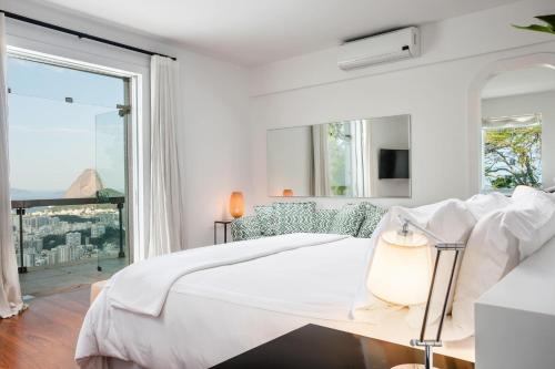 a white bedroom with a large bed and a large window at Vila Santa Teresa in Rio de Janeiro