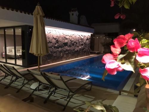a swimming pool with two chairs and an umbrella at Villa Adler Men Only in Playa del Ingles