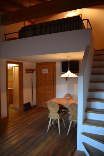 a dining room with a table and chairs and a staircase at Residence Miragolf in Madulain