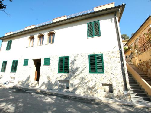 a white building with green shutters on it at Sogno Azzurro - ArgonautiVacanze in Porto Azzurro