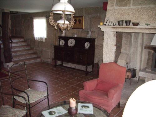 a living room with a red chair and a fireplace at Os Areeiros Turismo Rural & Bodega in Santa Cristina de Cobres