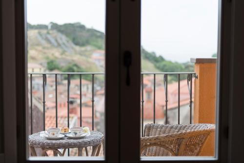 a table with two cups on top of a balcony at Antica Dimora Del Gruccione, Albergo diffuso in Santu Lussurgiu